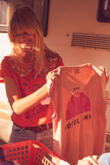 Sleeveless t-shirt w/ deep round neck . Old pink w/ "motel inn" print